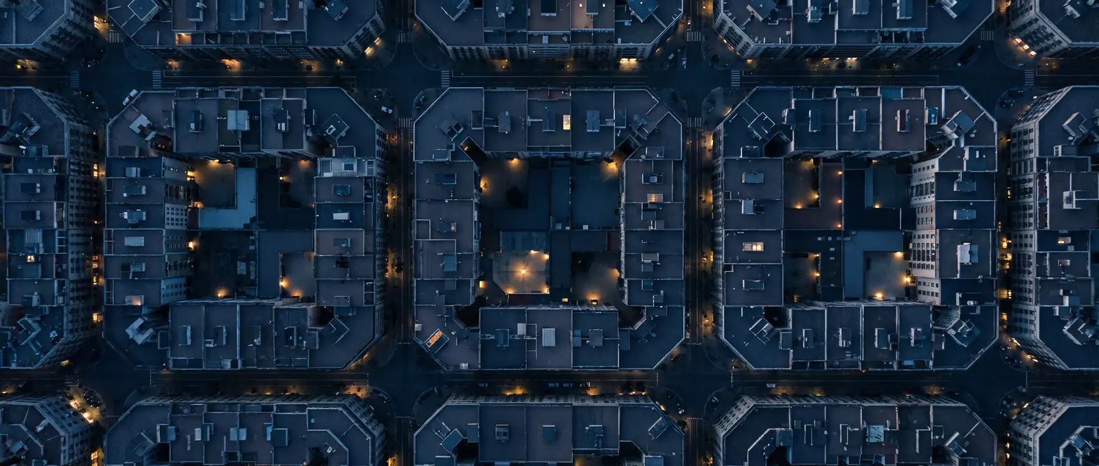 Vista aérea de manzanas de viviendas de una ciudad al anochecer.